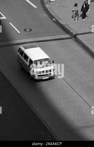 Eine vertikale Schwarz-Weiß-Aufnahme eines Volkswagen Bulli auf einer leeren Straße Stockfoto