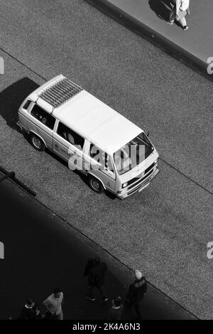 Eine vertikale Schwarz-Weiß-Aufnahme eines Volkswagen Bulli auf einer leeren Straße Stockfoto