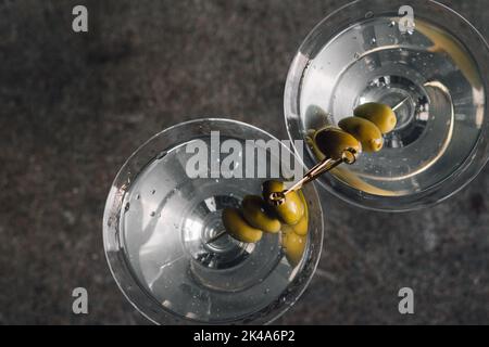Flache Ansicht von zwei martini-Cocktails mit je drei Oliven auf Gold-Picks Stockfoto