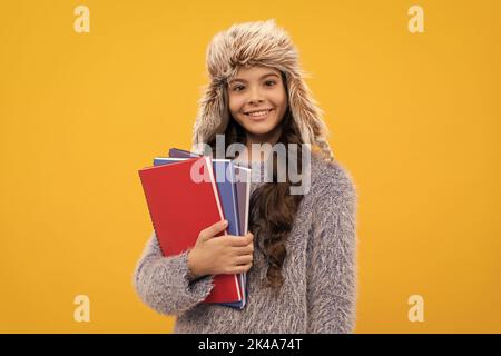 Glückliches Kind lange Haare in Hut mit Copybook auf gelbem Hintergrund, Bildung Stockfoto