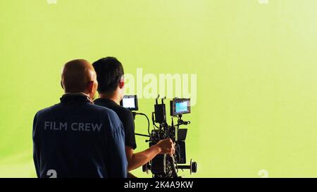 Fotografen-Team und Filmcrew und High-Definition-Online-Videokamera und Green-Screen-Hintergrund für Filmaufnahmen im großen Studio. Stockfoto