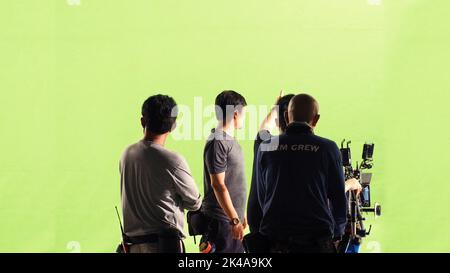 Fotografen-Team und Filmcrew und High-Definition-Online-Videokamera und Green-Screen-Hintergrund für Filmaufnahmen im großen Studio. Stockfoto