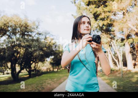 Die junge Touristenfrau, die den Sucher der Kamera näher an ihr Auge bringt, um ein Foto zu machen Stockfoto