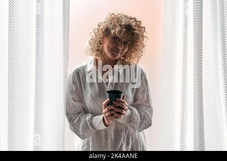Lächelnde Frau mit Tasse Kaffee zu Hause Stockfoto