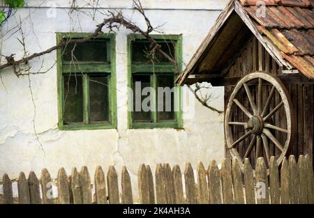 Arad County, Rumänien, ca. 2000. Altmodischer Wasserbrunnen auf einem privaten Grundstück mit einem jahrhundertealten traditionellen Haus. Stockfoto