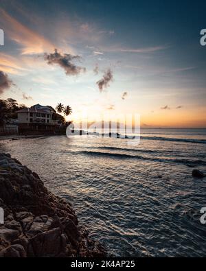Eine wunderschöne tropische Landschaft mit Silhouetten von Palmen am Meer unter einem bunten Himmel bei Sonnenuntergang Stockfoto