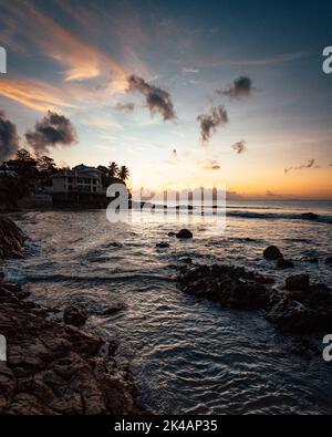 Eine wunderschöne tropische Landschaft mit Silhouetten von Palmen am Meer unter einem bunten Himmel bei Sonnenuntergang Stockfoto