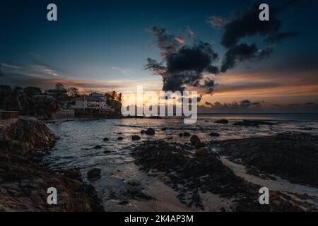 Eine wunderschöne tropische Landschaft mit Silhouetten von Palmen am Meer unter einem bunten Himmel bei Sonnenuntergang Stockfoto