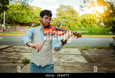 Violinist Künstler spielt eine Melodie im Freien, Portrait des Mannes, der Violine im Freien spielt. Nahaufnahme des Geigers, der auf der Straße spielt. Bild eines Stockfoto