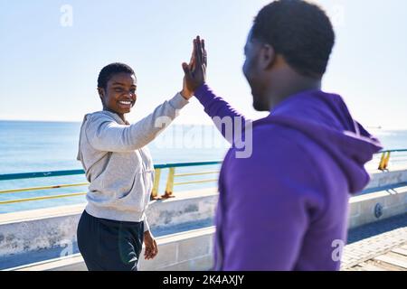 Mann und Frau tragen Sportkleidung mit hohen fünf Händen am Meer angehoben Stockfoto