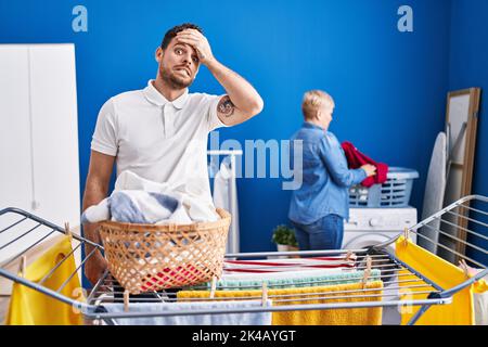 Hispanische Mutter und Sohn hängen Kleidung an der Wäscheleine gestresst und frustriert mit Hand auf Kopf, überrascht und wütend Gesicht Stockfoto