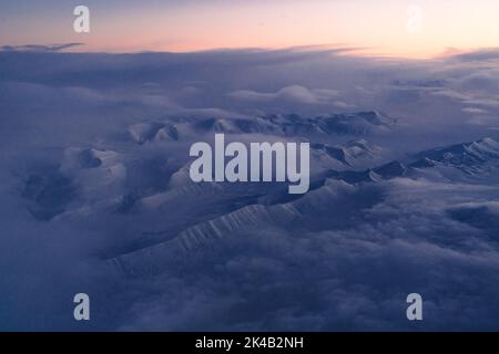 Einzigartige Luftaufnahmen von gefrorenen verschneiten Winterlandschaften der Spitzbergen Berge und Küste, aufgenommen von Flugzeug / Drohne bei Sonnenuntergang Stockfoto