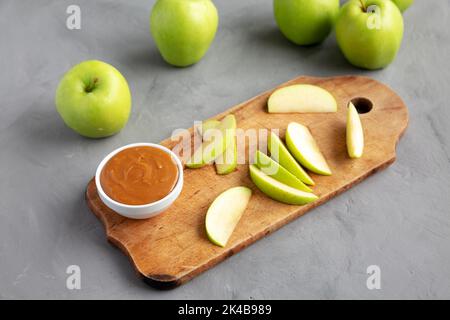 Hausgemachter Karamell-Apfel-Dip auf einem rustikalen Holzbrett, Seitenansicht. Stockfoto