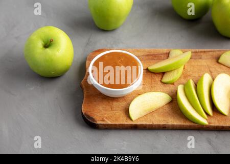 Hausgemachter Karamell-Apfel-Dip auf einem rustikalen Holzbrett, Seitenansicht. Stockfoto