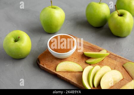 Hausgemachter Karamell-Apfel-Dip auf einem rustikalen Holzbrett, Seitenansicht. Stockfoto