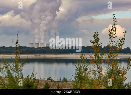 29. September 2022, Brandenburg, Cottbus: Blick über die Wasseroberfläche der zukünftigen Cottbuser Ostsee, die im ehemaligen Tagebau Cottbus-Nord entsteht, mit den dampfenden Kühltürmen des Braunkohlekraftwerks Jänschwalde im Hintergrund. Hier soll in wenigen Jahren der zukünftige Cottbus East Lake entstehen. Mitte April 2019 begann die Überschwemmung der ehemaligen Tagebaumine Cottbus-Nord. Das Energieunternehmen Lausitz Energie Bergbau AG (LEAG) lässt für das Hochwasser Wasser aus der Spree über den Hammergraben in den Tagebau fließen. Für Anwohner, Stockfoto