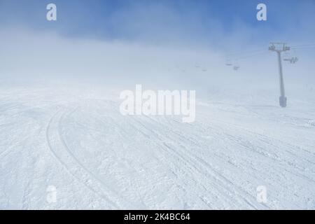 Skigebiet Piste mit eingeschränkter Sicht mit niemand am Morgen. Schlechte und wechselhafte Wetterbedingungen Stockfoto