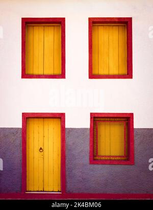 Zweistöckige façade mit Fenstern und Türen aus gelb lackierten Holzplatten mit roten Zierleisten in Sabará, Minas Gerais, Brasilien Stockfoto