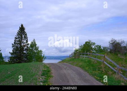 Eine leere Schotterstraße, die im Frühjahr zum Mjosa-See in Norwegen führt Stockfoto