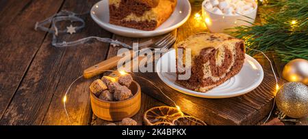 Eine Torte auf einem weihnachtlichen Hintergrund mit einer brennenden Girlande. Frohe Weihnachten und Frohes neues Jahr. Stockfoto