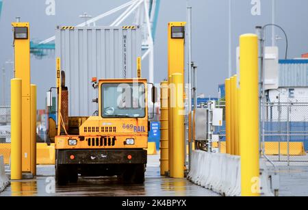 Ein von einem Hafenfahrzeug gezogener Transportcontainer kommt zum Scannen mit auf Lastwagen montierten Strahlungserkennungssystemen an, die von US-Zoll- und Grenzschutzbeamten betrieben werden. Er befindet sich im Hafen von Miami in Miami, Florida, 07. Dezember 2015. CBP-Foto von Glenn Fawcett Stockfoto