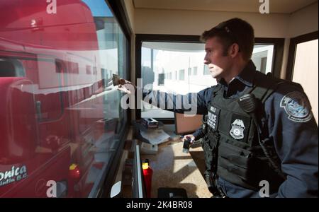 Ein US-Zoll- und Grenzschutzbeauftragter überprüft die Identifizierung des LKW-Fahrers, während er den US-Kontrollpunkt der Frachtvorinspektion im Hafen von Otay Mesa, Kalifornien, passiert, 23. Juni 2016. An jedem Tag stehen mehrere hundert Lastwagen auf der mexikanischen Seite der Grenze an, um importierte Produkte zu liefern, die auf die Überprüfung durch Zollbeamte warten. Eine wachsende Anzahl von Reedereien nutzt die Cargo Pre-Inspection von CBP, die vertrauenswürdigen Spediteuren eine schnellere und effizientere Möglichkeit bietet, Produkte an US-Einzelhändler zu liefern. CBP-Foto von Glenn Fawcet Stockfoto