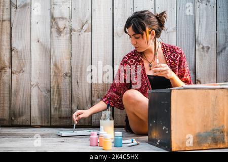 Junge Malerin taucht den Pinsel vor dem Malen in die Palette Stockfoto