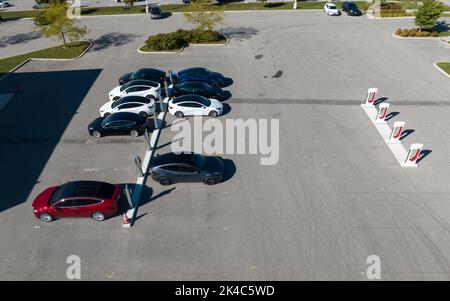 Eine Luftaufnahme über einer Tesla Ladestation mit bunten Tesla Fahrzeugen in einem Händlerbetrieb, Tesla Supercharger, ist leer. Stockfoto