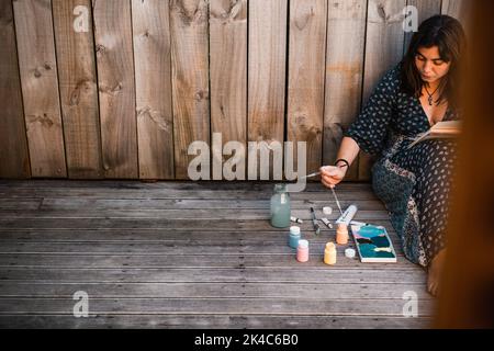 Junge Malerin mit dem Pinsel in der Hand, bevor sie ihn in die Farbe taucht Stockfoto