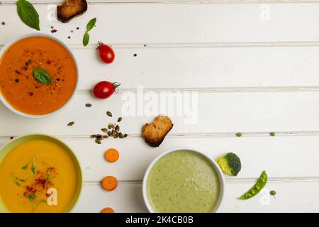 Horizontales Bild von Schüsseln aus Karotten, Brokkoli und Tomatensuppen auf weißem Holz, mit Platz für Kopien Stockfoto