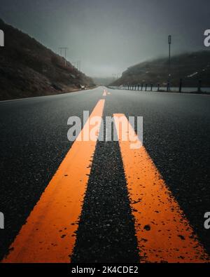 Eine vertikale Nahaufnahme von lackierten gelben Linien auf einer Straße Stockfoto