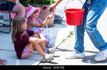 Eau Claire MI USA Juli 4 2022; eine Person übergibt Süßigkeiten an Kinder, während sie eine Parade am 4.. Juli beobachten Stockfoto