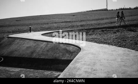 Eine Graustufenaufnahme von zwei Frauen, die auf einem schmalen, kurvigen Weg auf dem Land spazieren gehen Stockfoto