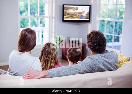 Familie schaut fern, während sie zu Hause auf dem Sofa sitzt Stockfoto