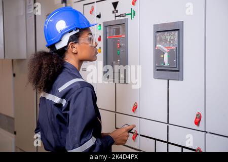 Elektrische junge asiatische Frau Ingenieur Untersuchung Wartungsschranksystem elektrisch und mit Tablet im Kontrollraum in der Industriefabrik, Techniker Stockfoto