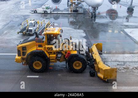 Ein Bulldozer schaufelt Schnee von einer verschneiten Piste Stockfoto