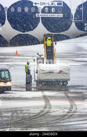 HELSINKI, FINNLAND, 15 2022. FEBRUAR, Verladen des Gepäcks auf das Flugzeug bei starkem Schneefall Stockfoto