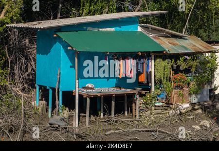 Ein einfaches Haus an einem schlammigen Flussufer. Stockfoto