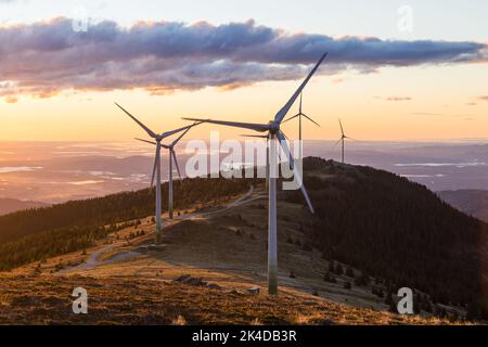 Eine Gruppe von Windmühlen auf einem Bergrücken in Österreich während des Sonnenaufgangs in Österreich Stockfoto