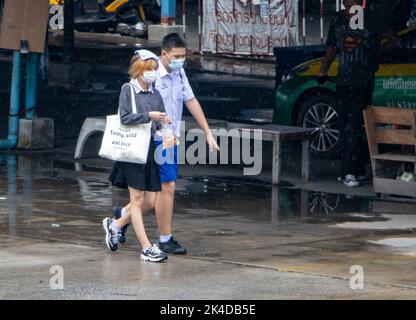 SAMUT PRAKAN, THAILAND, SEP 23 2022, Ein Junge und ein Mädchen in Schuluniformen gehen auf einer nassen Straße Stockfoto