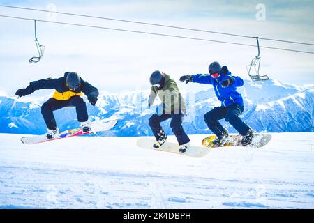 Drei Snowboarder springen in der Luft gemeinsam im Winterresort auf Urlaub im kaukasus zum Spaß Stockfoto