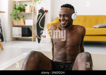 Glücklicher junger afrikanischer Mann, der sich nach einer individuellen Ausbildung zu Hause entspannt Stockfoto