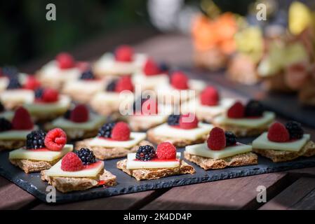 Eine seitliche Nahaufnahme von Puffs mit Creme und Beeren auf dem Holztisch mit verschwommenem Hintergrund Stockfoto