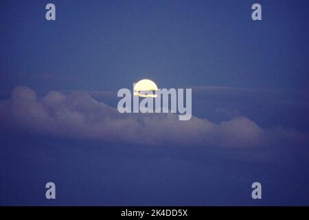Eine malerische Aussicht auf den Vollmond, gesehen durch Wolken am Nachthimmel Stockfoto