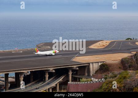 Airbus von TAP Portugal nähert sich der Start- und Landebahn des Flughafens Madeira LPMA, auch bekannt als Funchal Airport und Santa Catarina Airport, neben einem geschäftigen h Stockfoto