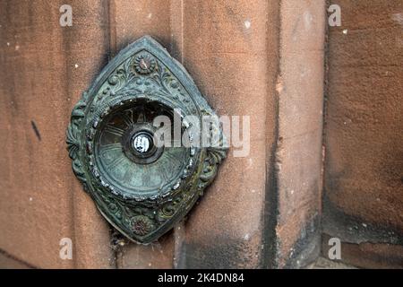 Ende des 19.. Jahrhunderts/Anfang des 20.. Jahrhunderts bronzene elektrische Türglocke in einer roten Sandsteinwand Stockfoto