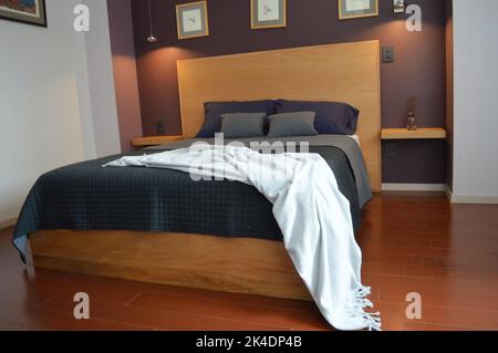 Bettgestell, Schlafzimmer mit Matte auf dem Boden, Tontopf im Hintergrund, Holzcredenza und Spiegel. Stockfoto