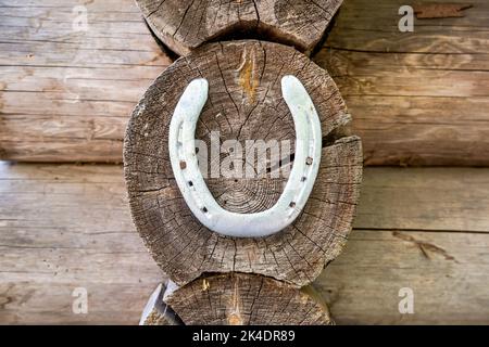 Altes Metallhufeisen, das an der Wand eines Holzhauses hängt Stockfoto