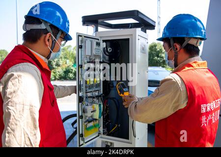 TAIZHOU, CHINA - 2. OKTOBER 2022 - Ein Mitarbeiter unterstützt Autobesitzer bei der Überprüfung des Betriebs von Ladehählen für Elektrofahrzeuge an einem Ladehautdemonstrat Stockfoto