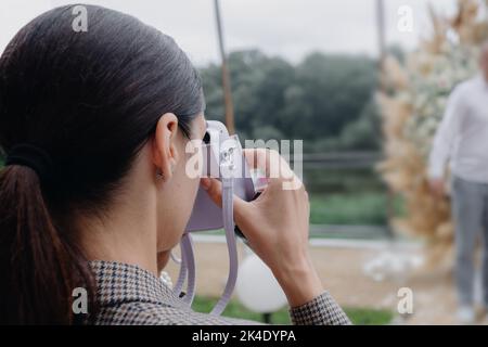 Ein Mädchen fotografiert die Gäste einer Hochzeit auf einer polaroid Stockfoto